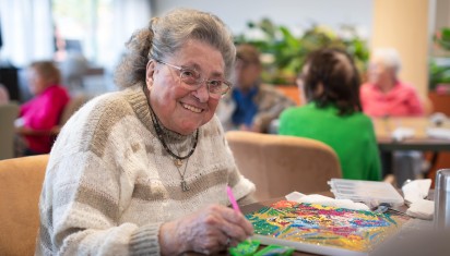 mevrouw maakt een kunstwerk met kralen