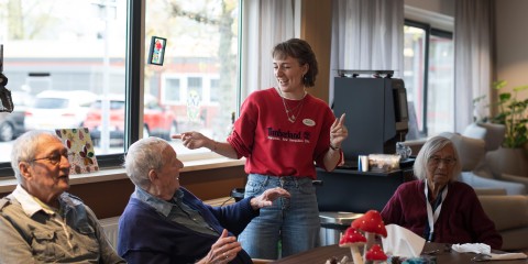 medewerker lachend met bewoners om de tafel