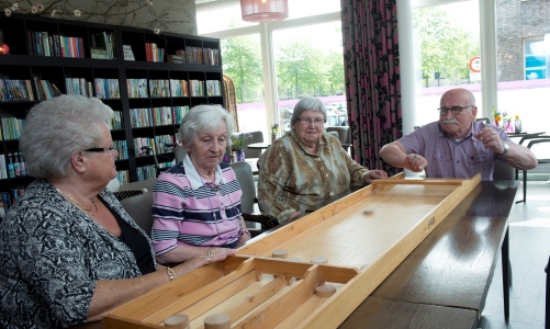 Een aantal senioren sjoelen in Huis van de Buurt Floriande