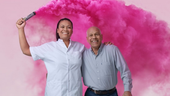 Vrolijk vrouwelijke verpleger met gekleurde roze wolk naast een oudere man