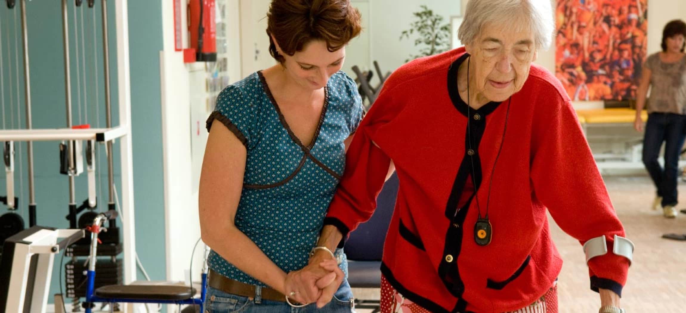 Ergotherapeut helpt oudere vrouw om te lopen met krukken