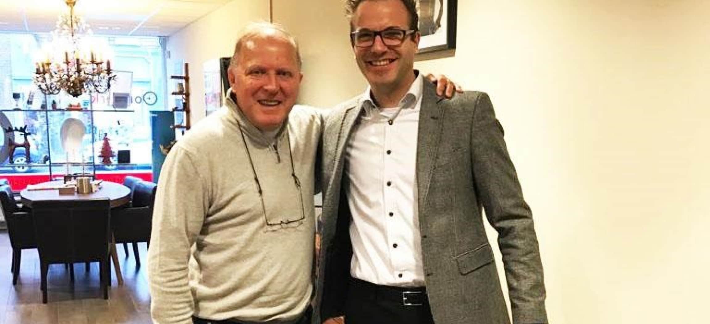 Twee mannen slaan arm om elkaar heen, in woonkamer