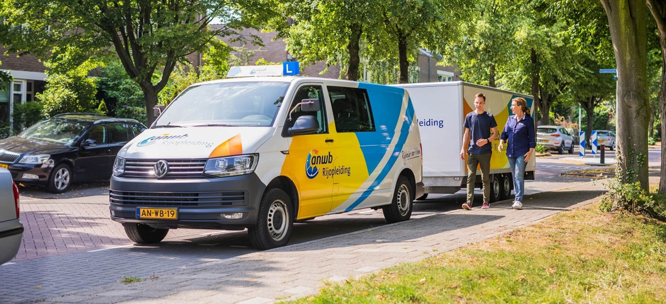 Rijles busje van ANWB Rijopleiding met aanhanger geparkeerd langs stoep in woonwijk