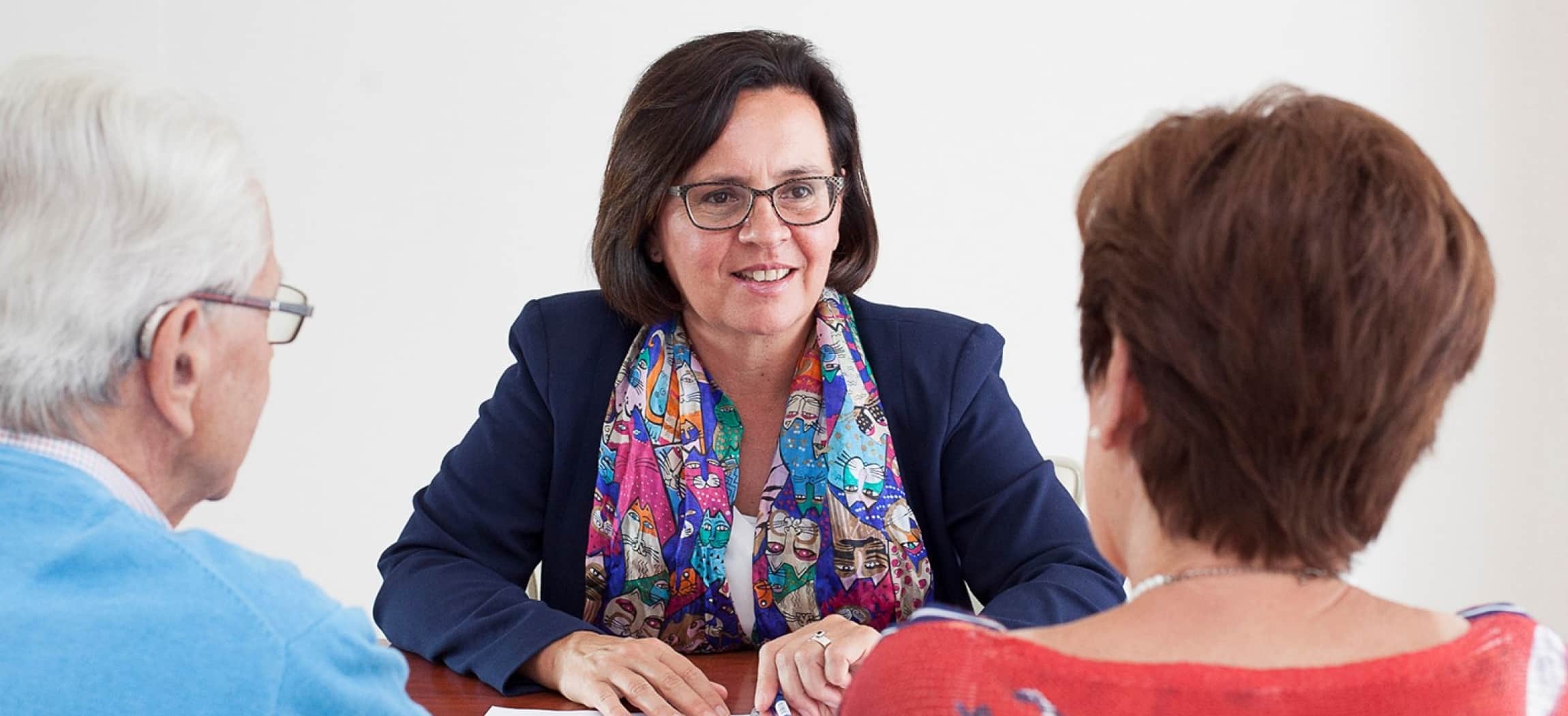 Vrouw met bril en colbertjasje geeft advies advies aan man en vrouw