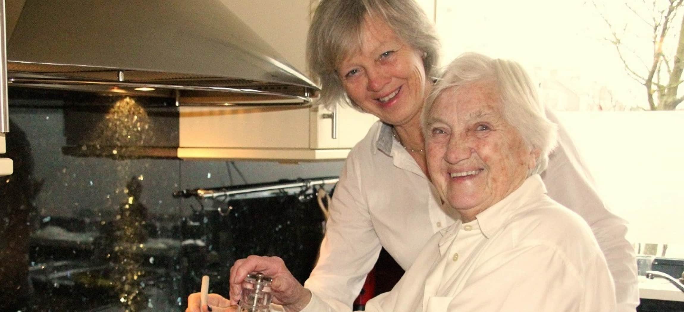 Twee oudere vrouwen in keuken met witte blouses