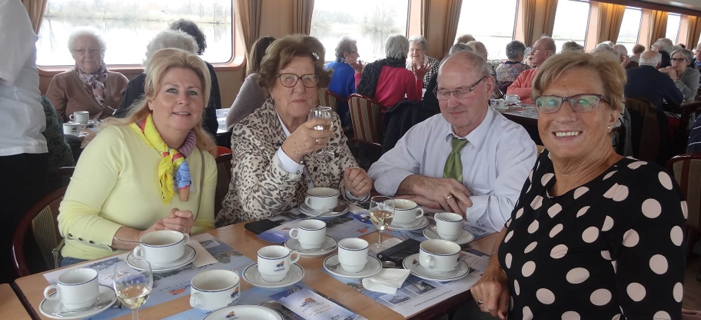 Ouderen drinken koffie aan tafel tijdens boottocht op de Rijn
