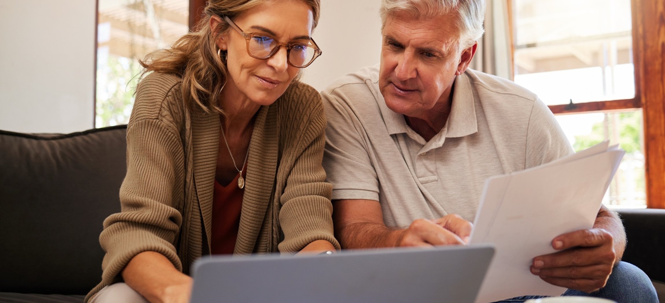 Twee vrouwen aan tafel met kopje koffie, de jongere vrouw houdt documenten vast en praat