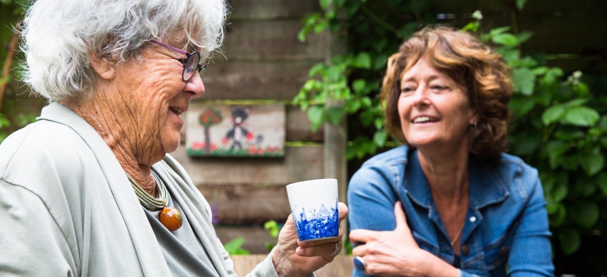 Twee oudere vrouwen in keuken met witte blouses