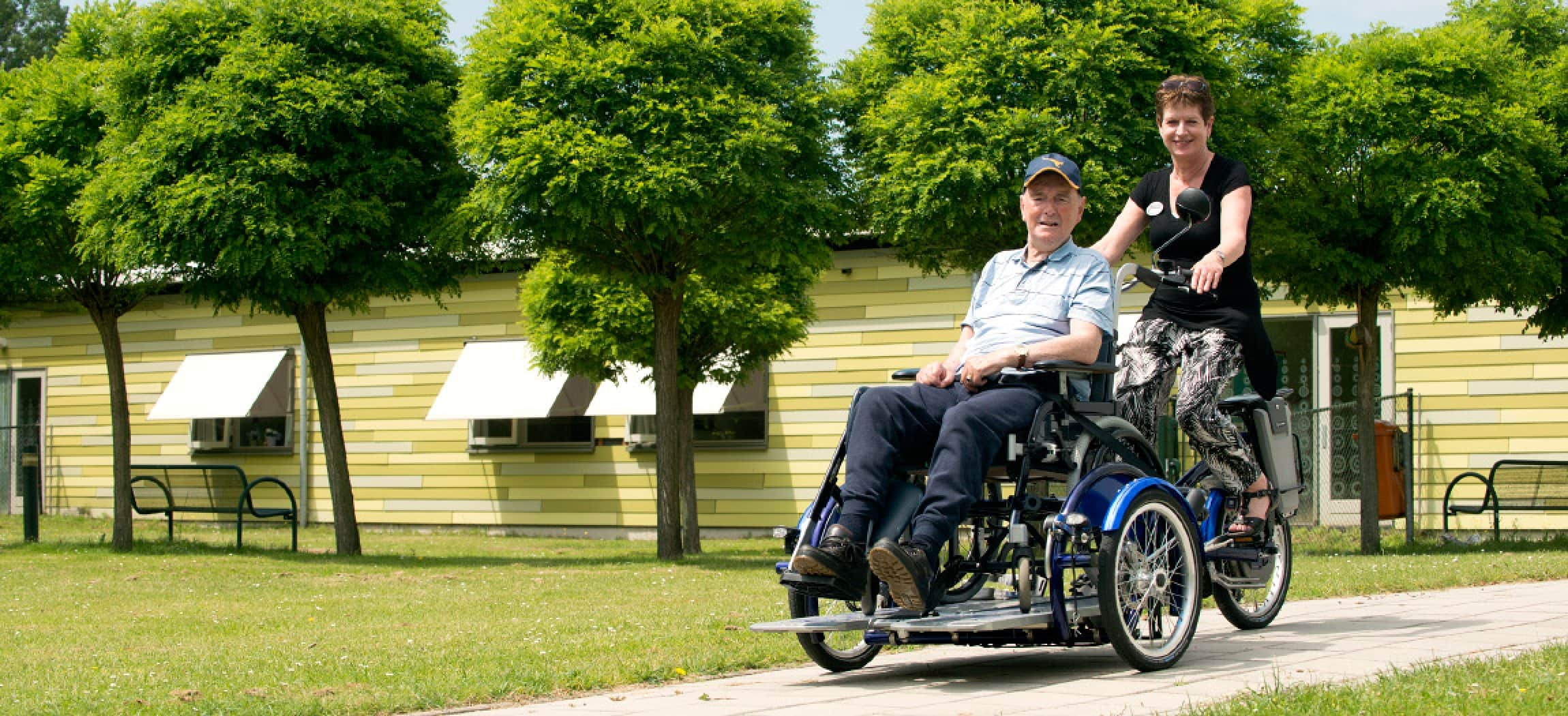 Rolstoelfiets met oudere man in rolstoel en verzorgende - rolstoeltransportfiets