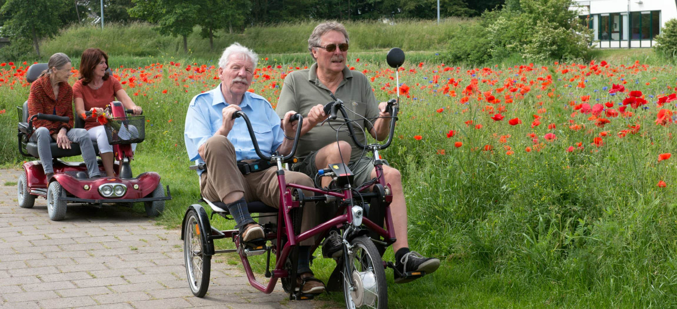 Duofiets en duo-scooter rijden buiten bij veld met rode klaprozen