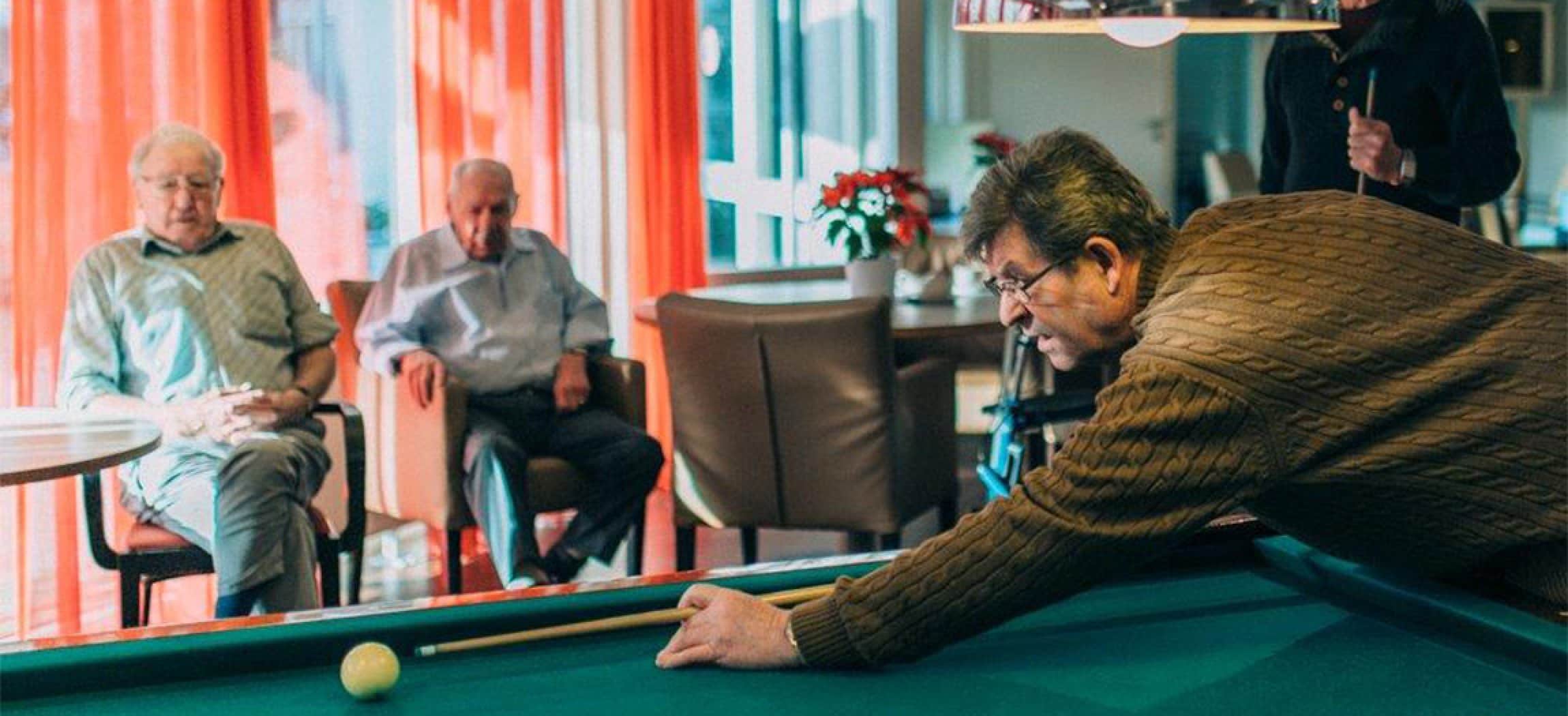 Biljarttafel en oudere mannen die naar biljartspel kijken