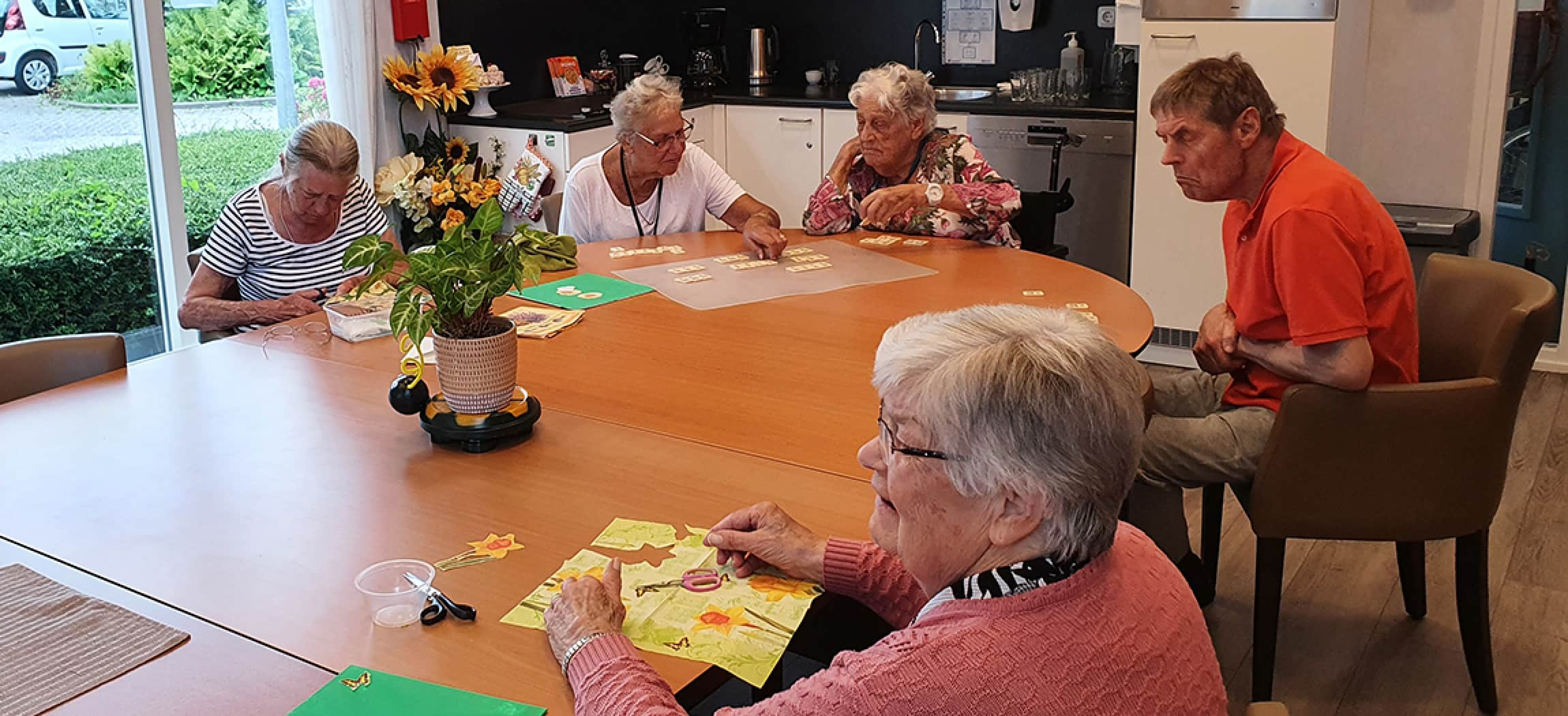 Blije oude vrouw met wit haar verzorgt samen de geraniums buiten op terras