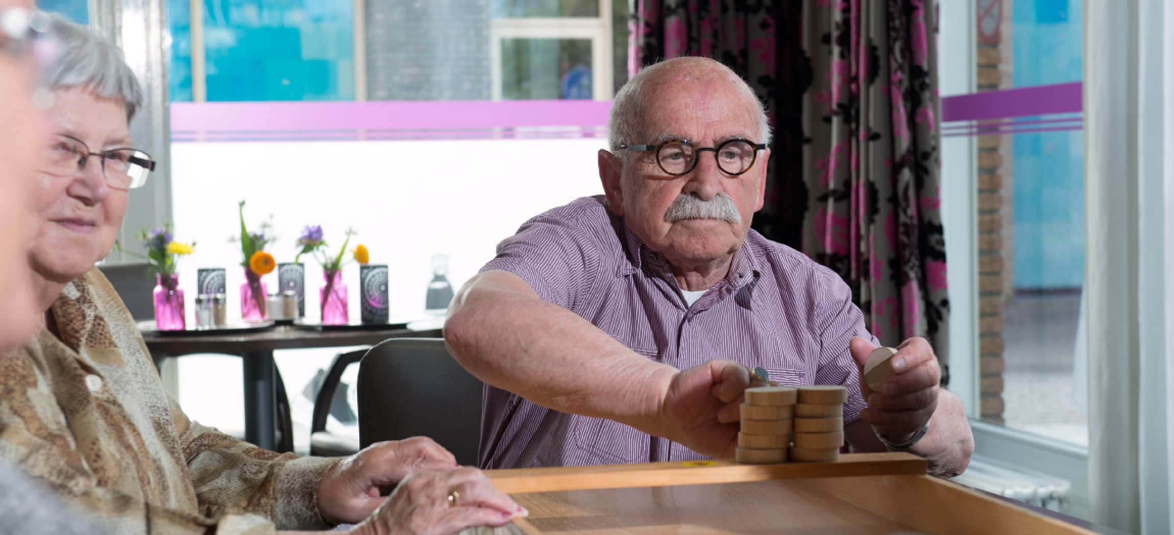 Sjoelen: oudere man met snor en bril speelt het Oud-Hollandse spel sjoelen