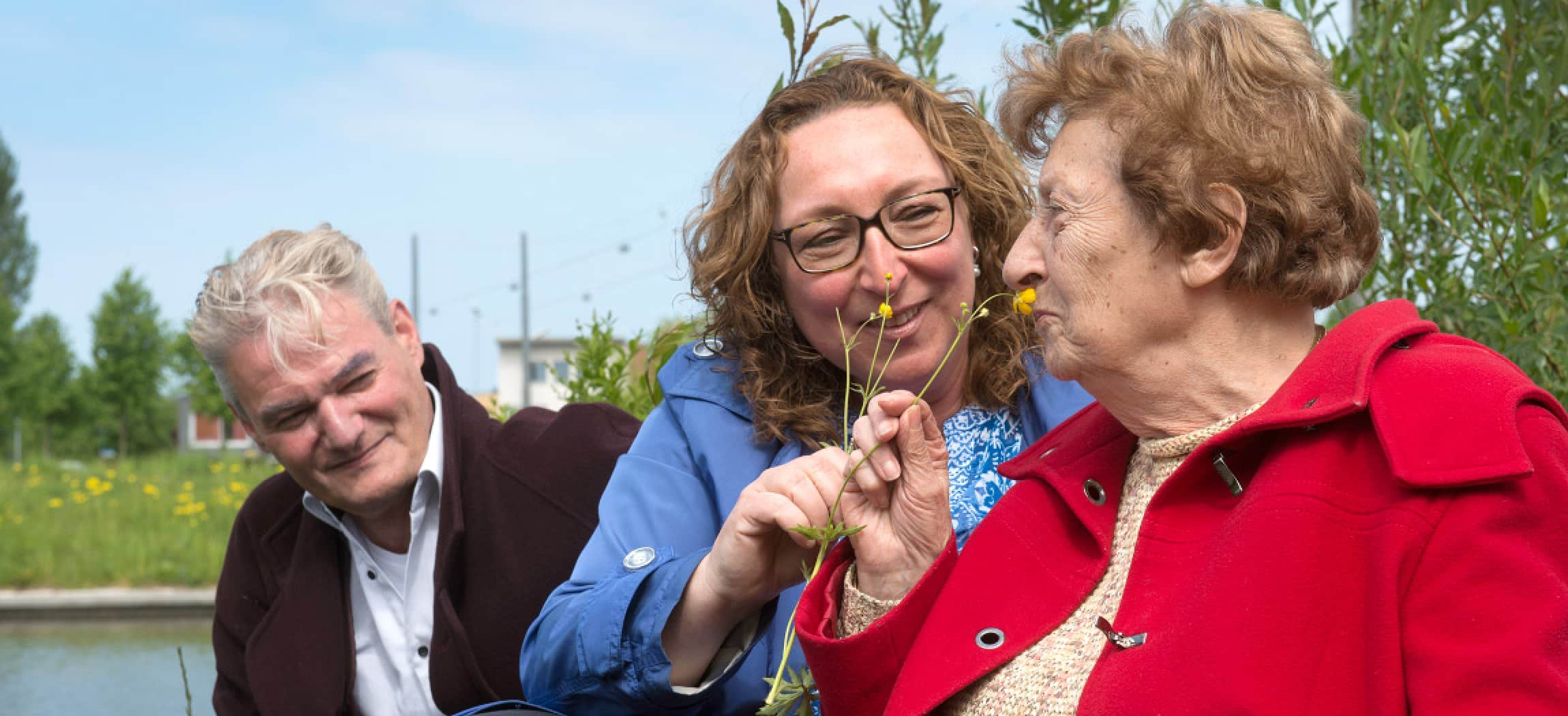 Jonge en oudere vrouw ruiken aan een bloem in de natuur