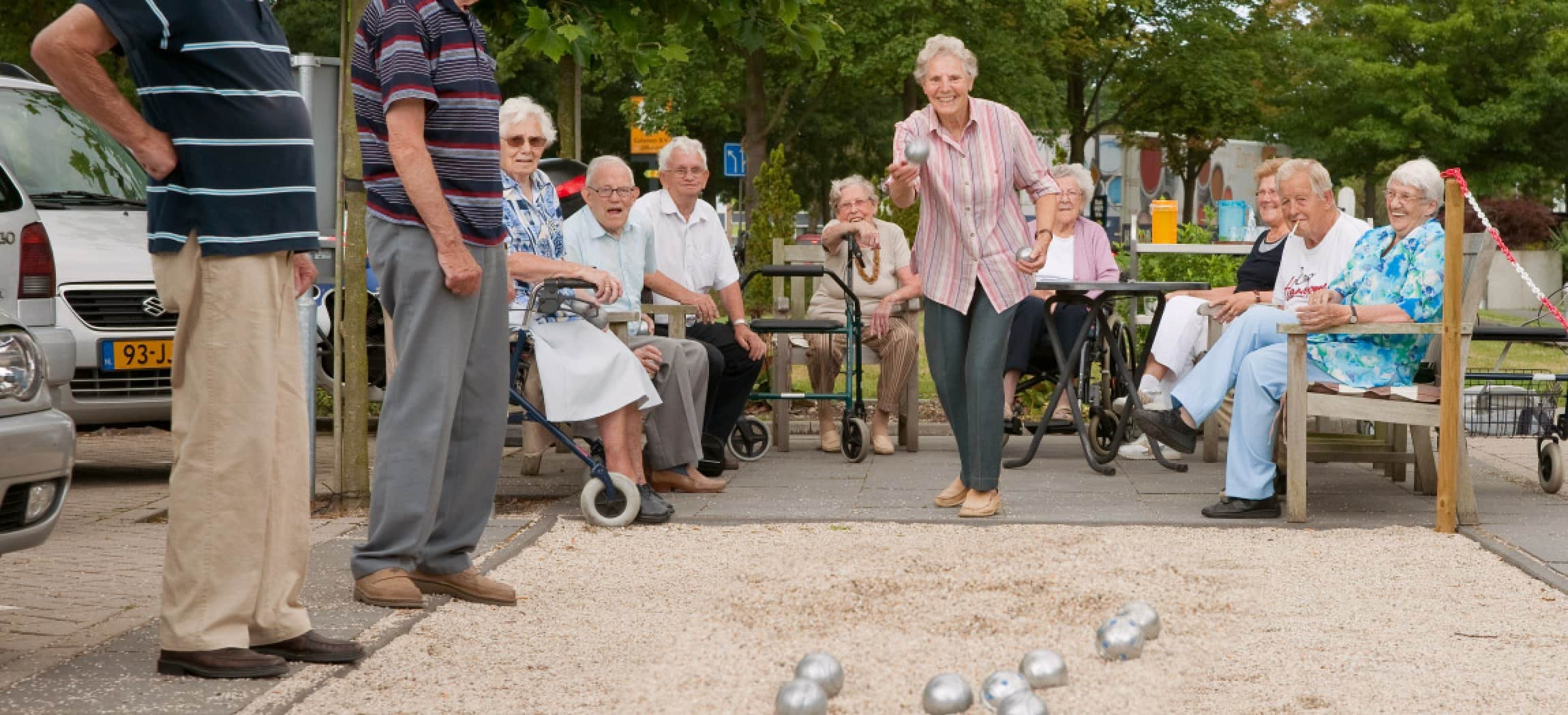 Vrolijke groep ouderen speelt Jeu de Boules op zomerse avond