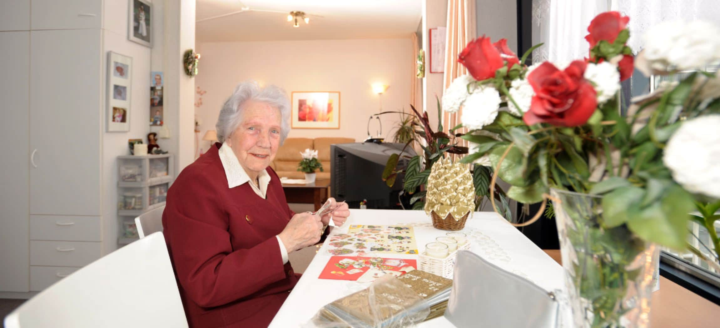 Vrouw met poëzieplaatje, schaar, ansichtkaarten en bos rozen in woonkamer