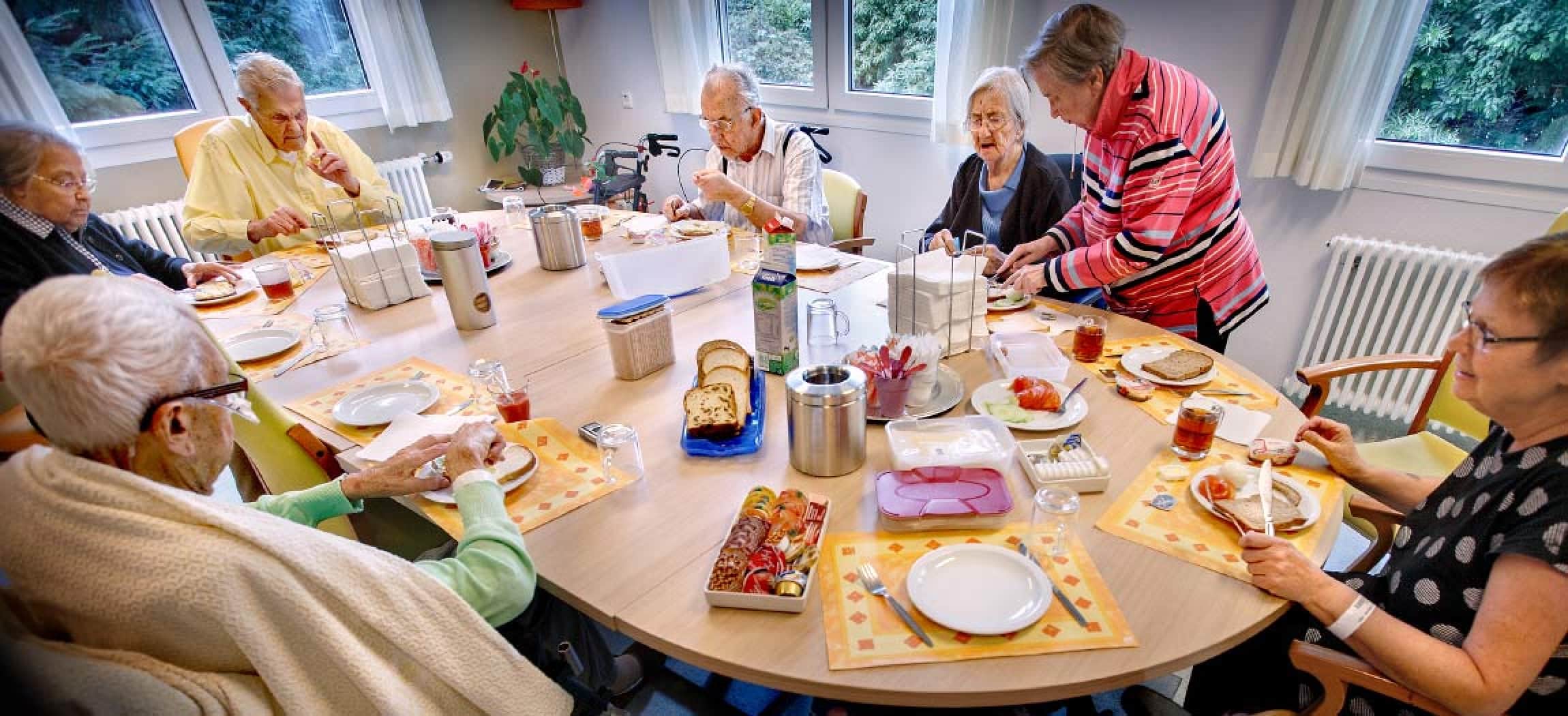 Groep ouderen in revalidatieafdeling eten samen aan tafel
