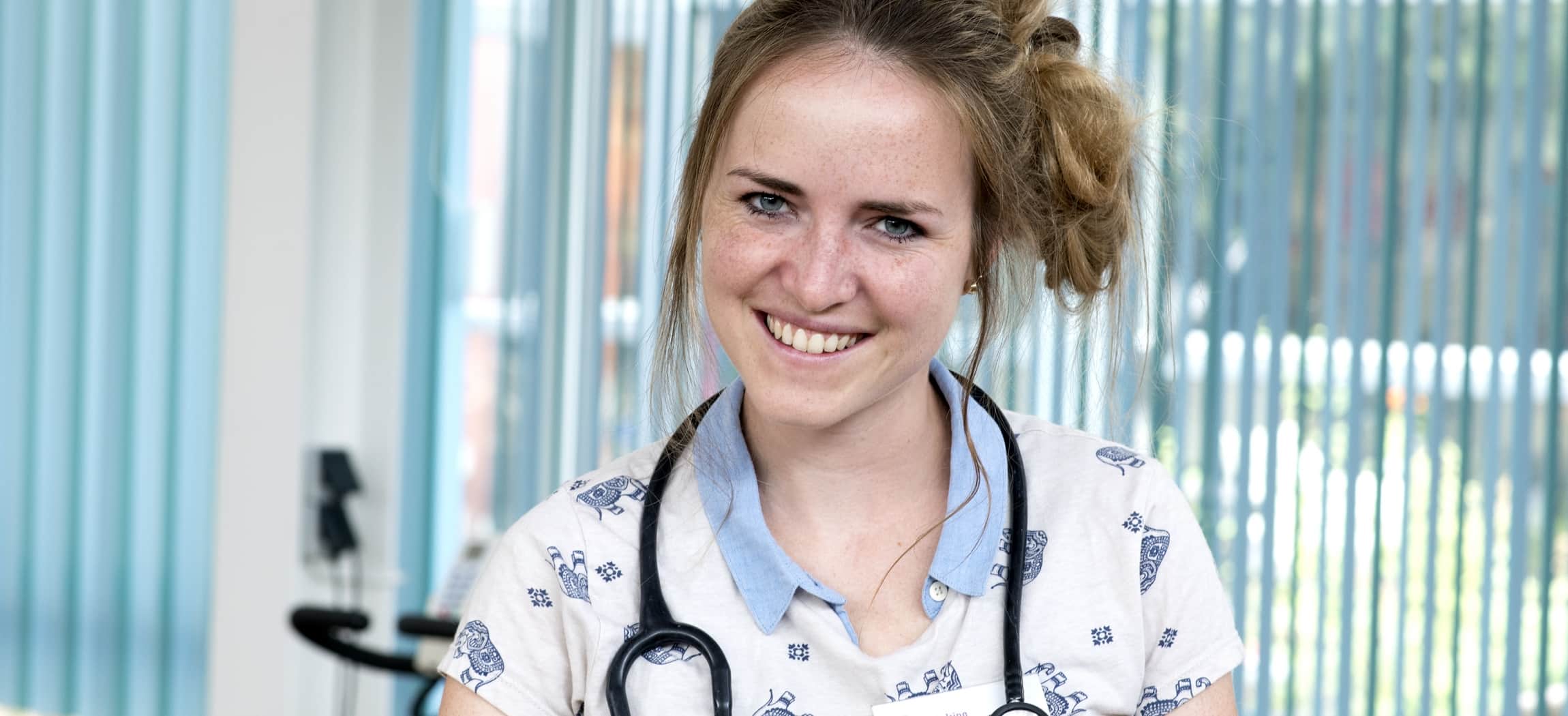 Arts jonge vrouw met stethoscoop en opgestoken haar, in opleiding tot Specialist Ouderengeneeskunde SOG