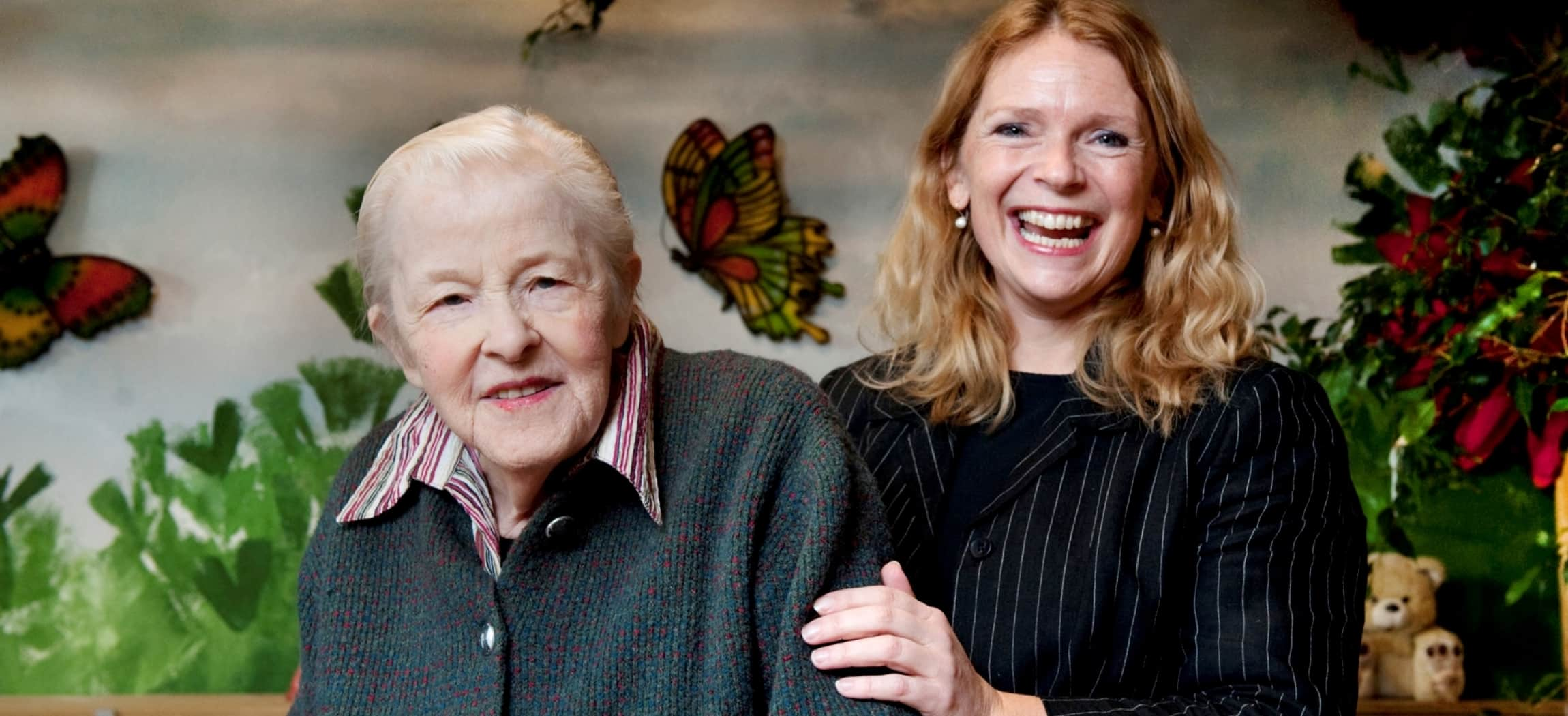 Oude vrouw met lieve lachende dochter voor een schilderij met vlinders