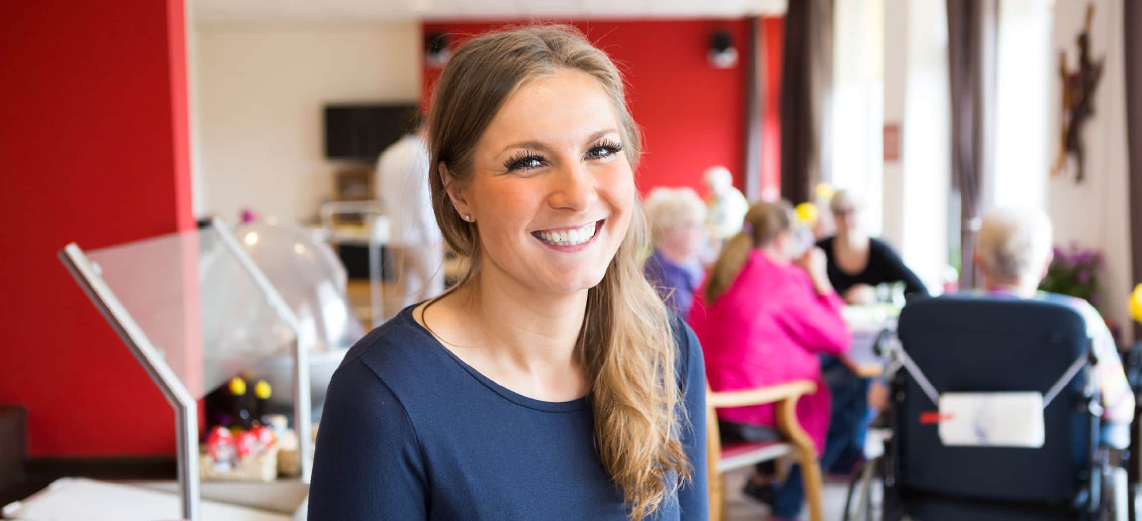 Jonge vrouw lang blond haar, op achtergrond beelden van een bejaardenhuis