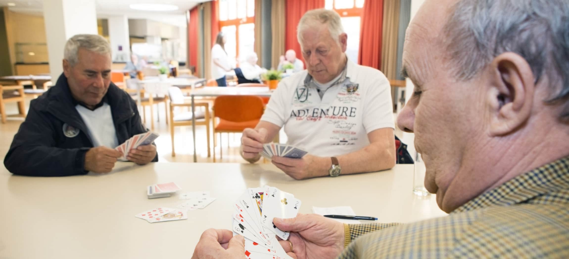 Drie mannen senioren spelen een kaartspel