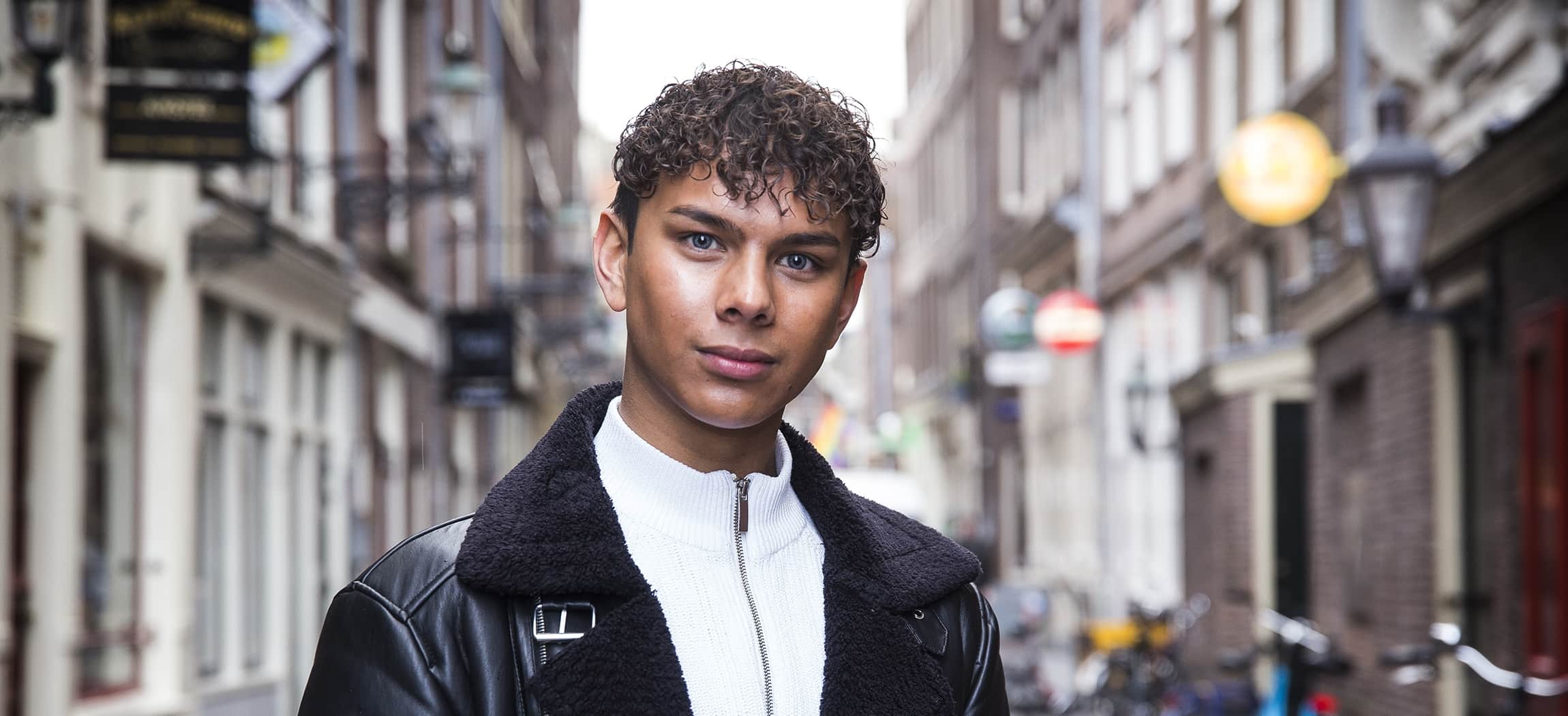 Student Jairo staat in een straat in Amsterdam en kijkt in de camera