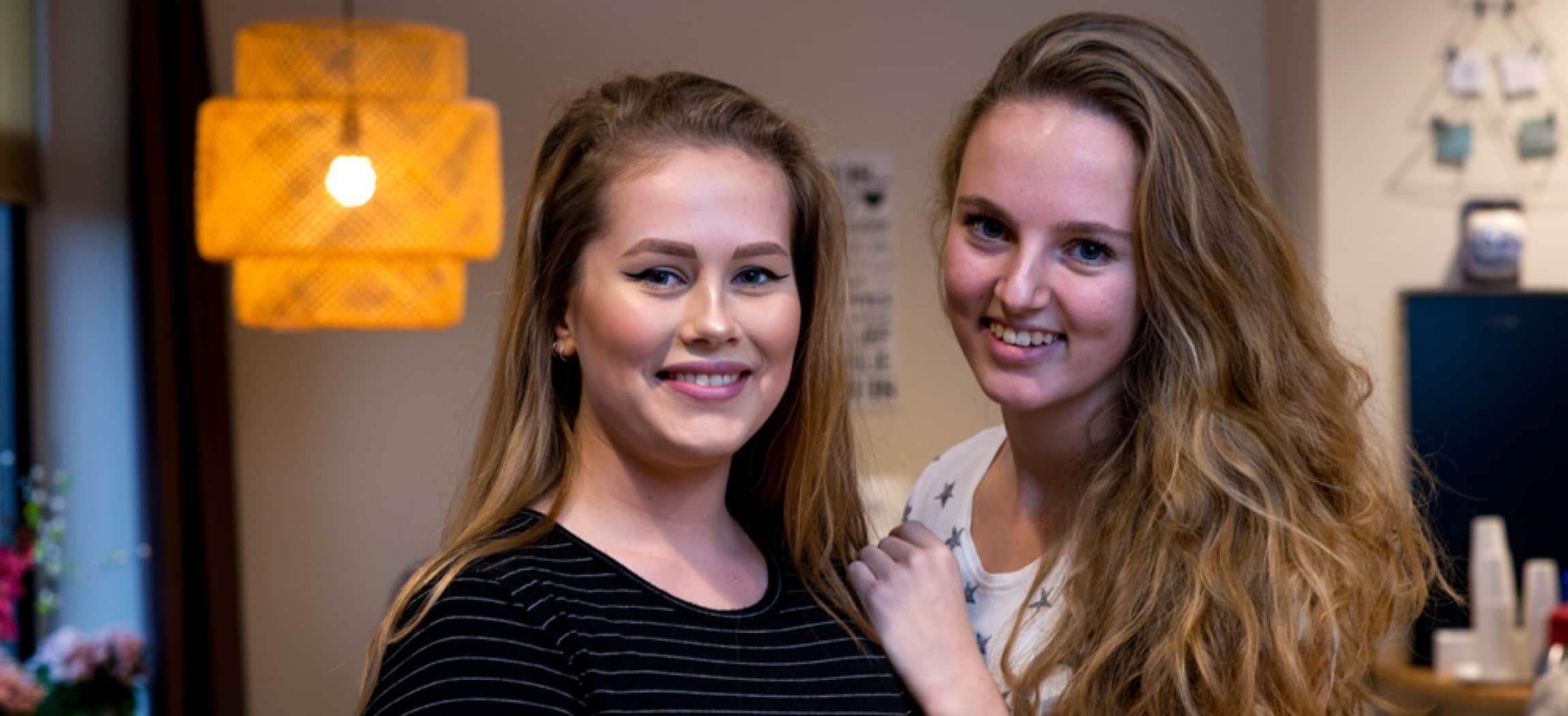 Twee jonge verpleegkundige in opleiding in huiskamer verpleeghuis met gele lamp
