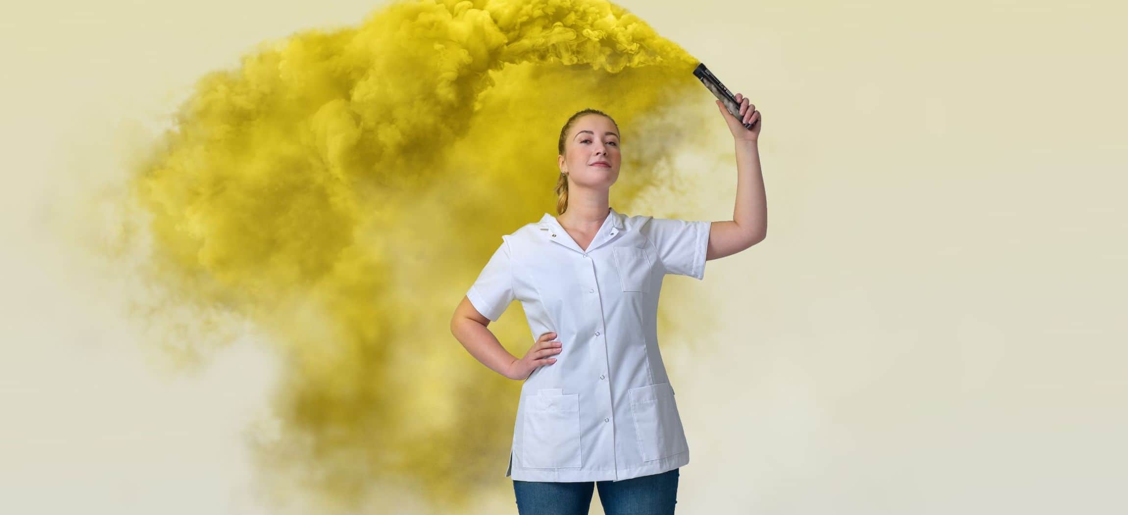 Vrouwelijke verzorgende in wit uniformjasje houdt fakkel vast met gele rook