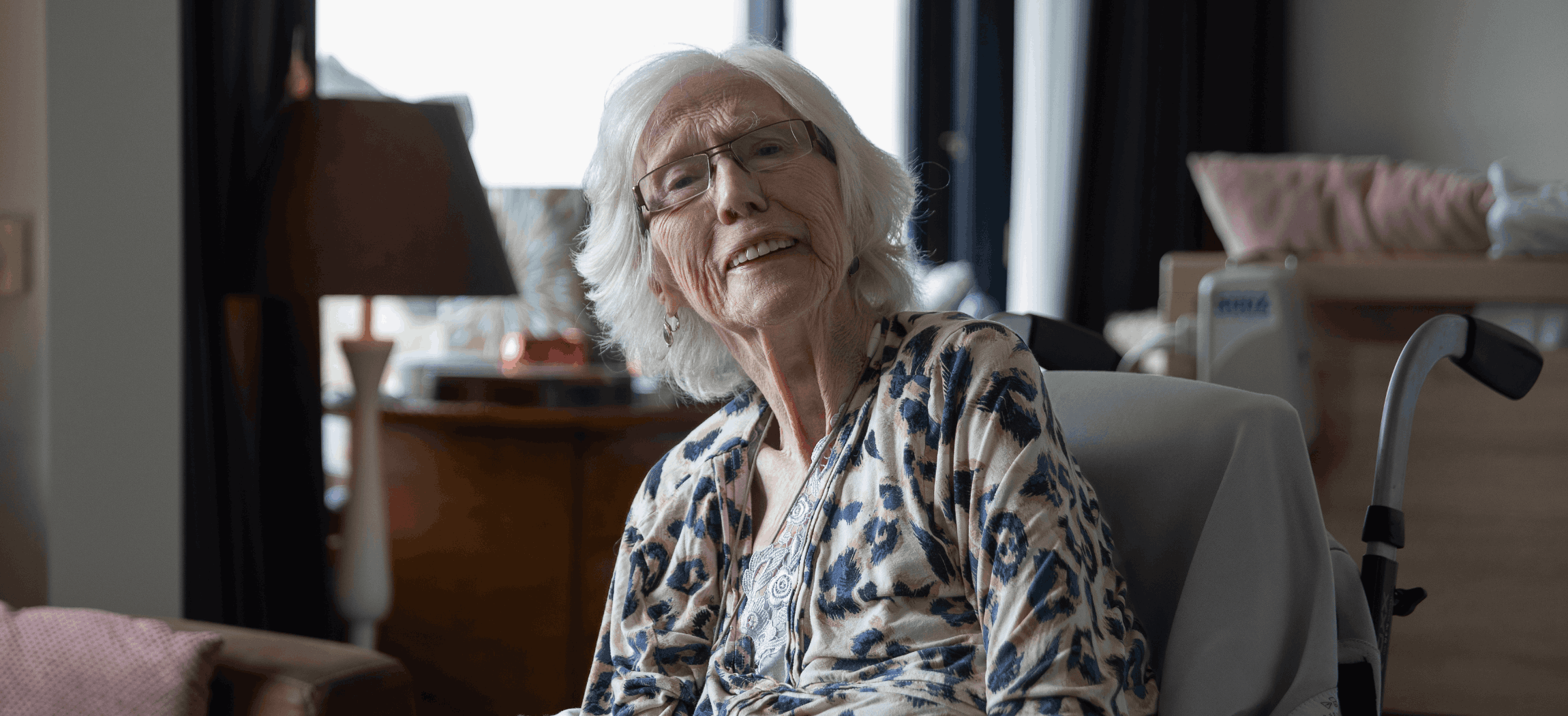 Verzorgende met krullend haar geeft oude vrouw drinken met rietje