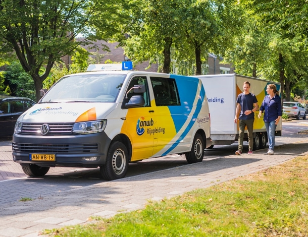 Rijles busje van ANWB Rijopleiding met aanhanger geparkeerd langs stoep in woonwijk