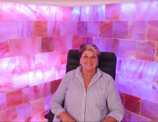Muur van roze zouttegels met een vrouw zittend in een stoel
