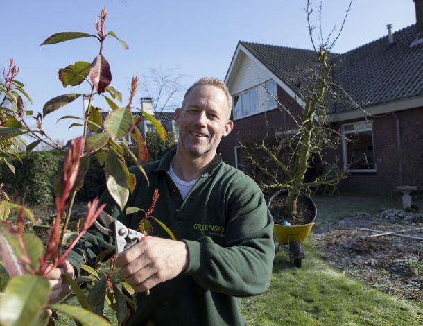 Tuin in aanleg met tuinman in groene sweater en snoeischaar