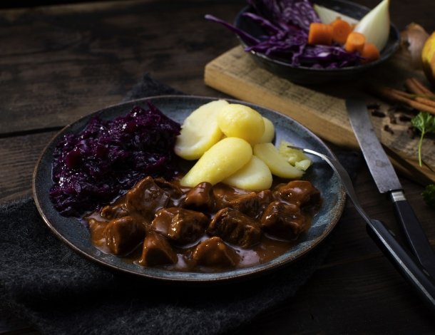Vrouw overhandigt een bordje eten wortelen sperziebonen aan man met overhemd en spencer
