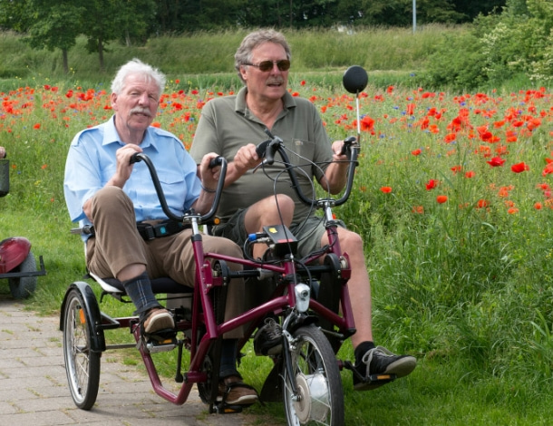 Duofiets en duo-scooter rijden buiten bij veld met rode klaprozen
