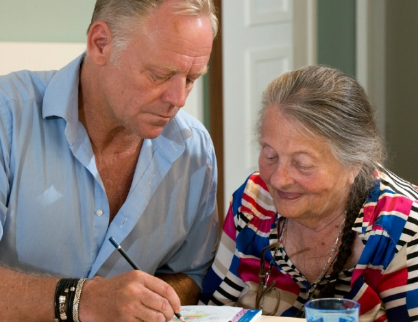 Man maakt tekening voor een oudere en blij kijkende vrouw