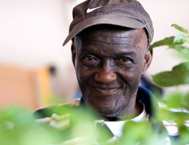 Vrolijke oudere man met donkere huidskleur en groene kamerplanten