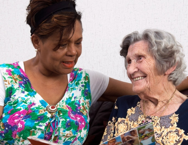 Verzorgende praat gezellig met oudere vrouw op een bank