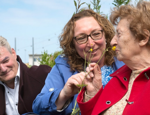 Jonge en oudere vrouw ruiken aan een bloem in de natuur