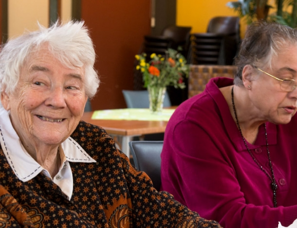 Lieve oude vrouw kijkt vrolijk om zich heen in verpleeghuis