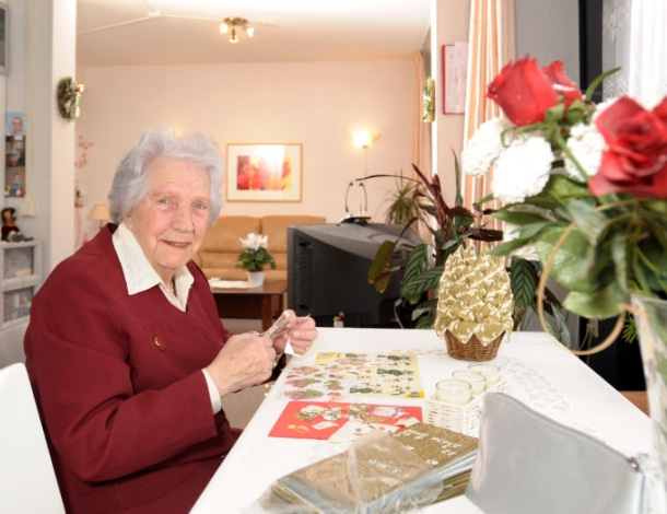 Vrouw met poëzieplaatje, schaar, ansichtkaarten en bos rozen in woonkamer