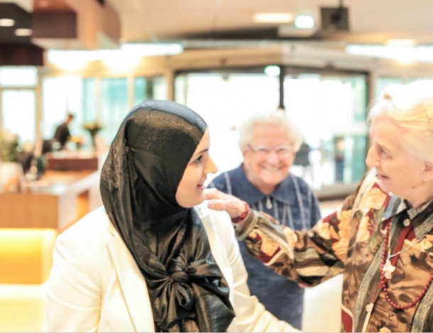 Oudere vrouwen praten enthousiast met jongere vrouw met zwarte hoofddoek of hijab