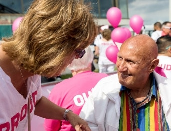 Tijdens Canal Pride kijkt oudere man blij en enthousiast met zwarte flaphoed